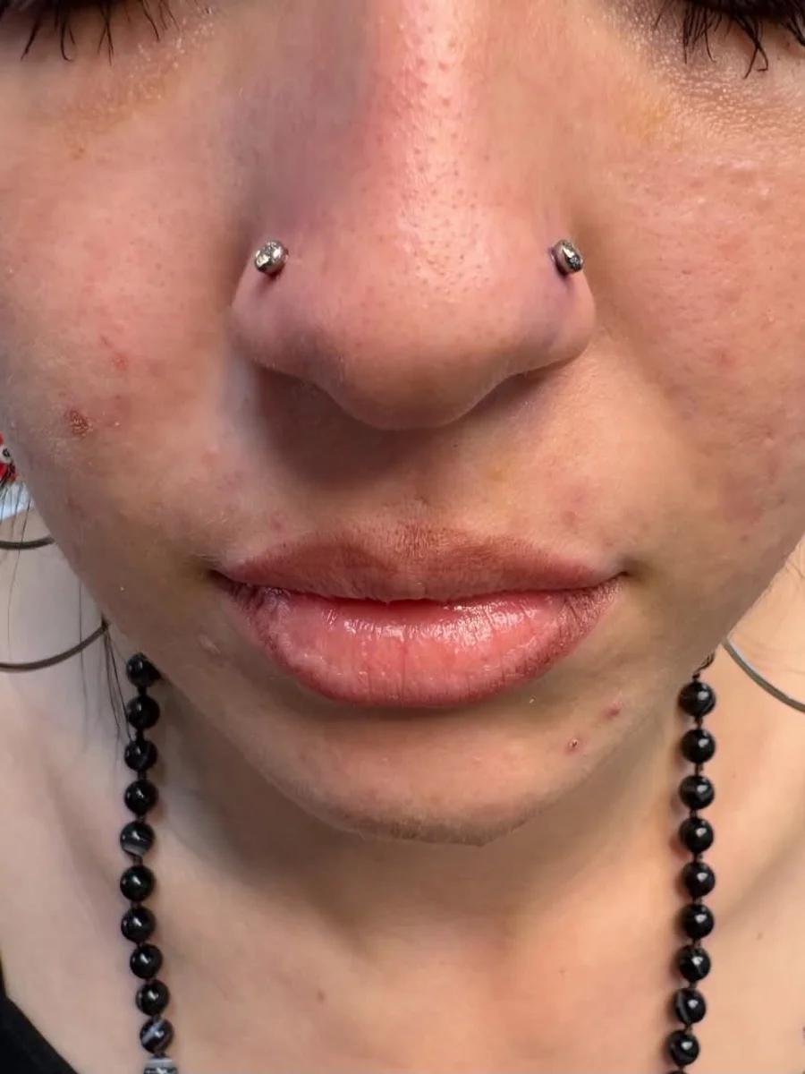 Matching nostril piercings with a crystal stud on each side of the nose