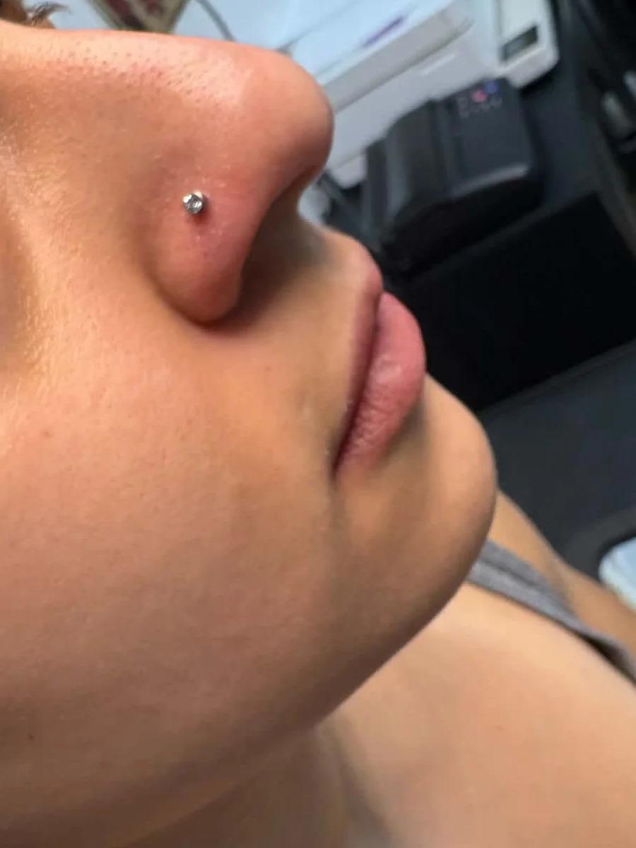 Fresh nostril piercing with a small crystal stud, seen from below