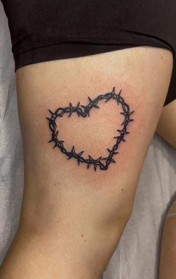 Fine line barbed wire heart tattoo with edgy romantic design and detailed linework
