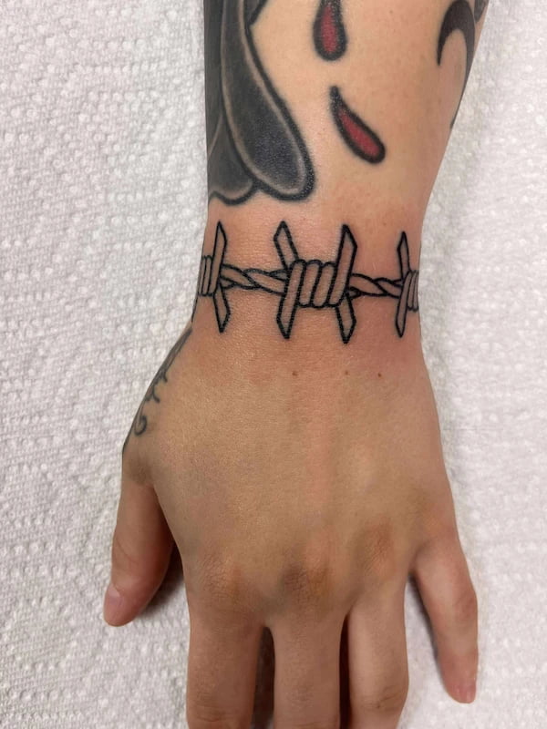 Fine line barbwire tattoo with detailed wire patterns and minimalist approach