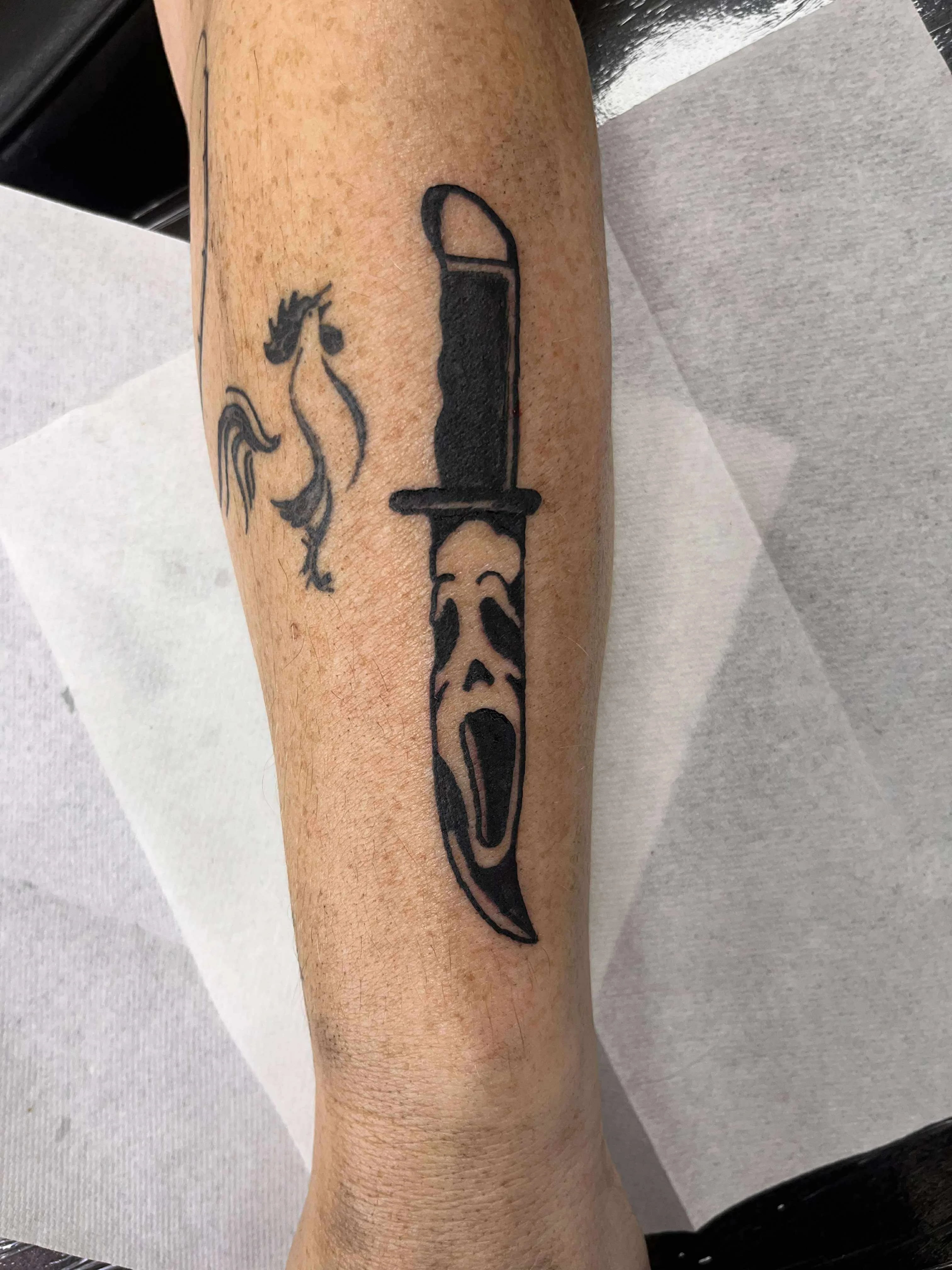 Fine line Scream knife tattoo with horror movie theme and minimal linework