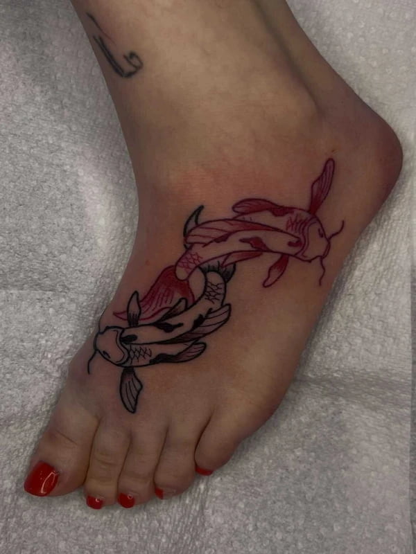 Traditional koi fish pair tattoo on foot with pink and black fish in circular pattern