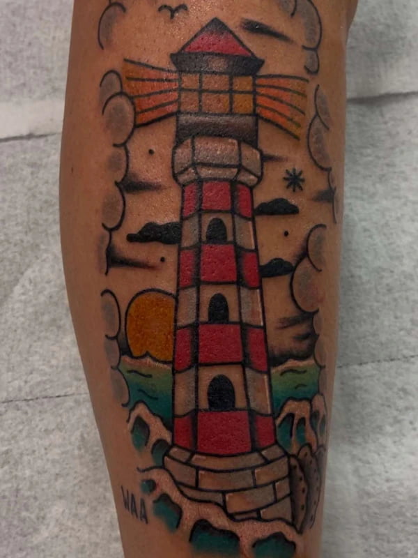 Traditional lighthouse tattoo with nautical elements and bold design