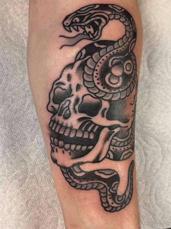 Traditional skull with snake wrapped around it tattoo in classic American traditional style