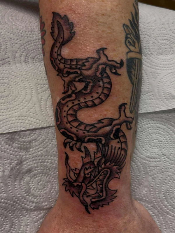 Traditional snake wrapped around dragon head tattoo with bold design elements